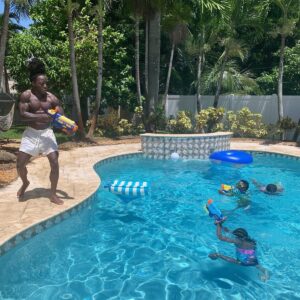 Ace Hood playing water gun with his twin daughter at his house