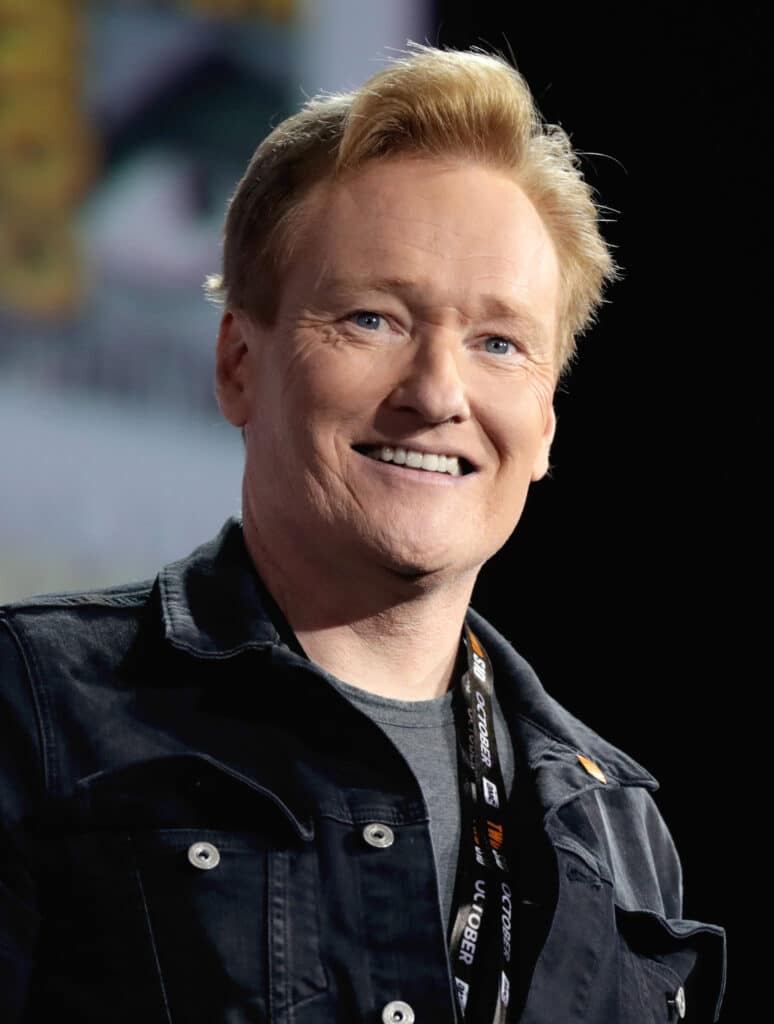 Conan is smiling at the audience.