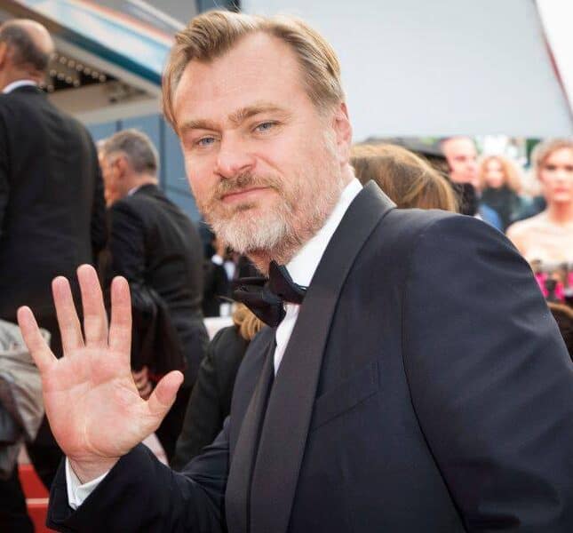 Christopher Nolan is waving at the camera.