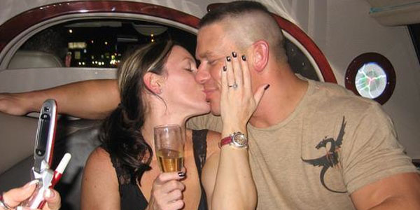 Liz and Cena kissing with a glass of champagne