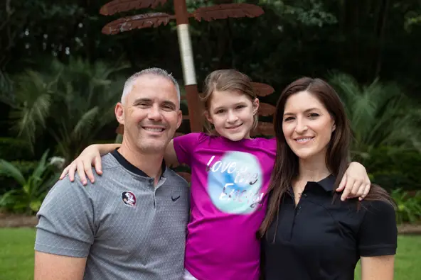 Florida State football coach Mike Norvell daughter Mila and wife Maria pose for a photo in front of a FSU Seminole spear in their backyard